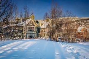 a large house in the snow with a snow covered yard at Les Eaux 227-3 by Tremblant Prestige in Mont-Tremblant