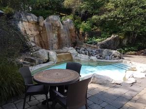 a pool with a table and chairs next to a waterfall at Les Eaux 227-3 by Tremblant Prestige in Mont-Tremblant