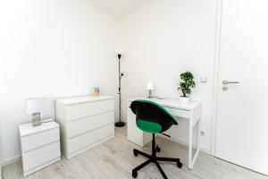 oficina blanca con silla verde y escritorio en Grand Appartement nahe Müggelsee en Berlín