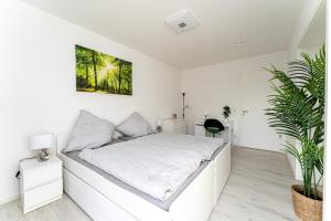 Un dormitorio blanco con una cama blanca y una planta en Grand Appartement nahe Müggelsee en Berlín