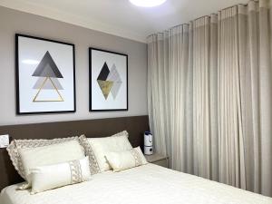 a bedroom with a bed and two pictures on the wall at Apartamento em Nova Aliança in Ribeirão Preto