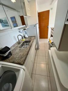 uma pequena cozinha com um lavatório e uma máquina de lavar roupa em UNU Rio Vermelho: Piscina, vaga, wifi, academia, + em Salvador