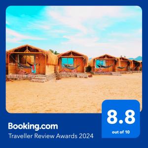 uma fileira de cabanas na areia numa praia em Cinderella Camp Nuweiba em Nuweiba