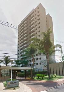 een hoog gebouw met palmbomen ervoor bij Apartamento em Nova Aliança in Ribeirão Preto