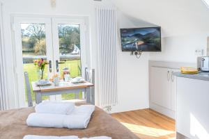 a living room with a table and a kitchen with windows at Romantic getaway in this stylish studio with views and free parking in Burneside