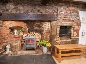 a stone fireplace with a stove and a table at The Brewhouse in Church Stretton