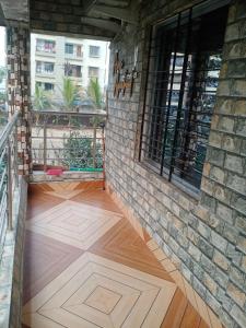 Areca Holiday Apartment في سيليغري: شرفة مع أرضية خشبية وجدار من الطوب
