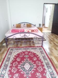 a bedroom with a bed with a red rug at Areca Holiday Apartment in Siliguri