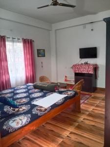 a bedroom with a bed and a table and a television at Areca Holiday Apartment in Siliguri