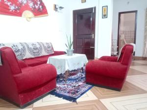 a living room with two red chairs and a table at Areca Holiday Apartment in Siliguri