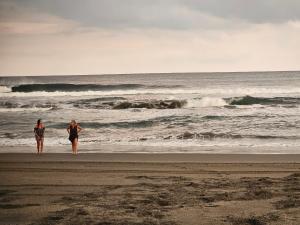 dwie kobiety stojące na plaży patrzące na ocean w obiekcie Cabañas Casa de Agua w mieście Boca del cielo