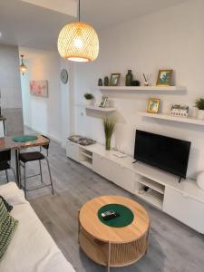 a living room with a couch and a tv and a table at Acogedor apartamento cerca del centro histórico de Málaga in Málaga