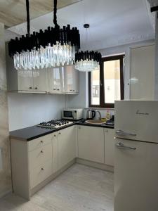 a kitchen with white cabinets and a chandelier at Apartament Simoni in Ploieşti