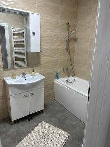 a bathroom with a sink and a tub and a mirror at Apartament Simoni in Ploieşti