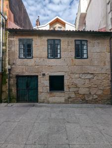 un edificio de piedra con dos puertas y ventanas de garaje en Pedra Nova - Céntrico, Lujoso en Pontevedra