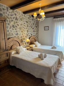 a bedroom with two beds and a stone wall at El Rincon del Moncayo in Vera de Moncayo