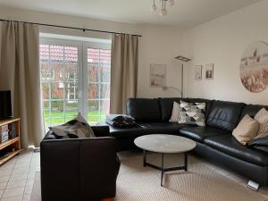 uma sala de estar com um sofá de couro preto e uma mesa em Semi-detached house, Nessmersiel em Neßmersiel