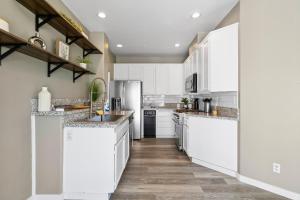 a kitchen with white cabinets and wooden floors at Olivia Oasis in Oxnard