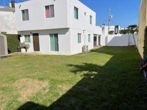 ein großes weißes Haus mit einem Rasenhof in der Unterkunft Casa confortable cerca de playa in Ciudad Madero