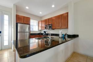 a kitchen with wooden cabinets and a granite counter top at Regal Oaks Resort Vacation Townhomes by IDILIQ in Orlando