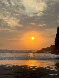 una puesta de sol en una playa con el océano y el sol en Alquiler departamento Asia - la alborada en Asia
