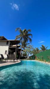 a swimming pool with two chairs and a palm tree at Pousada Lá em Casa in Barra Grande