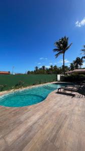 a swimming pool with a palm tree and blue water at Pousada Lá em Casa in Barra Grande