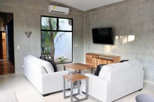 ein Wohnzimmer mit 2 weißen Sofas und einem TV in der Unterkunft hotelitos dos hijas in Playa Grande