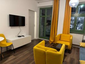 a living room with yellow chairs and a flat screen tv at GREENY in Wrocław
