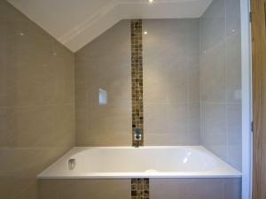 eine weiße Badewanne im Bad mit Fliesen in der Unterkunft Lavender Barn in Newquay + 9 Fotos