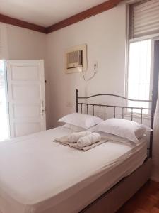 a bedroom with a bed with white sheets and a window at Quartos Aconchegantes prox Pelourinho, Metrô e Arena F Nova in Salvador