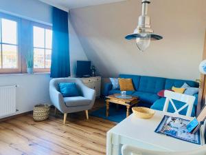 a living room with a blue couch and a chair at Kajüthus Apartment 1 in Fehmarn