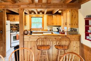 una cocina con armarios de madera y una barra con sillas en Peaceful Mountain Delight, en East Burke