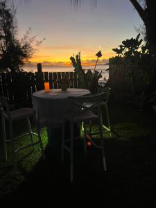 a table with two chairs and a sunset in the background at Pointe Venus Lodge in Mahina
