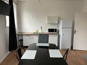 eine Küche mit einem schwarzen Tisch und Stühlen sowie einem Kühlschrank in der Unterkunft Résidence Le Gond in Le Gond + 3 Fotos