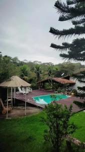 einen Pool mit einem Sonnenschirm und einer Terrasse in der Unterkunft Pousada Vale Encantado Macaé in Macaé