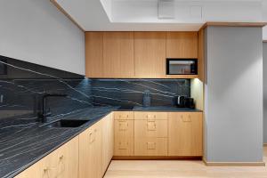a kitchen with a black counter top and wooden cabinets at Flatbook - City Center SPA Apartments Deo Plaza in Gdańsk