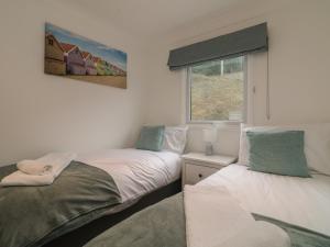 two beds in a room with a window at Ocean Blue in Porthtowan