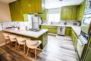 uma cozinha com armários verdes e uma ilha de cozinha com bancos em Las Vegas Oasis Home Primary em Las Vegas