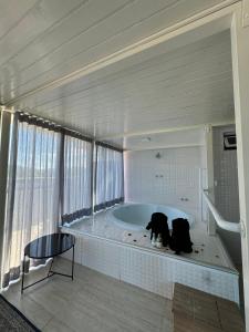 uma casa de banho com uma banheira com dois cães sentados nela em Duplex Ametista em Gravatal