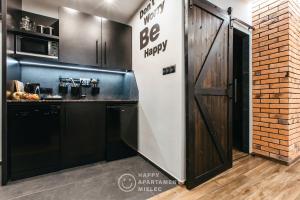 a kitchen with a be happy sign next to a door at Happy Night - Happy Apartamenty Mielec in Mielec