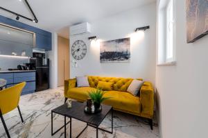 a living room with a yellow couch and a table at Sunset Premium Residence II & III in Dubrovnik