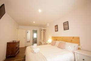 a bedroom with a large white bed with a wooden headboard at Apartamento Deluxe El balcón de la Trinidad Córdoba in Córdoba