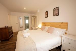 1 dormitorio con 1 cama blanca grande y cabecero de madera en Apartamentos El balcón de la Trinidad Córdoba en Córdoba