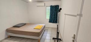 a small bedroom with a bed and a shower at JUNGLE HOUSE in Saint-Laurent du Maroni