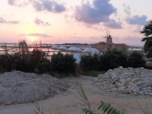 a sunset on the beach with a windmill in the background at ORO BIANCO in Marsala