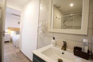 baño con lavabo, espejo y cama en La Trinidad Córdoba en Córdoba