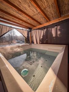 a pool of water in a building with a roof at Aloha Glamp - Domki z prywatnym jacuzzi & balia & sauna in Zagórnik