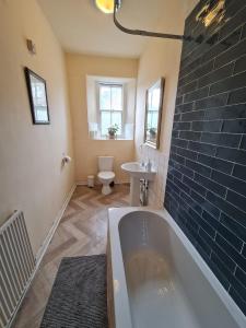 een badkamer met een bad, een toilet en een wastafel bij Apex Haymarket Station Apartment in Edinburgh