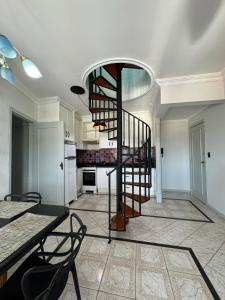 uma escada em espiral num quarto com uma cozinha em Duplex Ametista em Gravatal